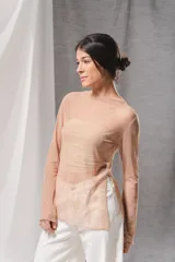 Blusa de tul transparente color beige, de manga larga, con escote bote y aberturas laterales en el ruedo. Presenta un diseño estampado en la parte inferior que simula la parte delantera de un pantalón de jean.