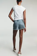 Shorts de jean de algodón, tiro alto, color azul claro desgastado. Presenta cinco bolsillos, cierre frontal con botón metálico y cremallera, y bajo desflecado con vuelta.