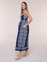 Vestido midi azul marino con bordados florales blancos, escote cuadrado, breteles anchos y falda amplia con bolsillos.