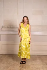 Vestido largo de seda color amarillo con estampado batik en tonos verde oliva y blanco. Escote en V con ribete de punto fino en cuello y mangas. Talle único.