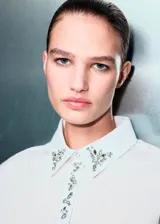 Camisa de popelín de algodón en color blanco, de corte recto y diseño clásico. Presenta cuello camisero con detalle de cristales decorativos, cierre frontal de botones ocultos y mangas largas con puños abotonados.