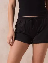 Conjunto de pijama de dos piezas marca René Rofé, compuesto por un top blanco de breteles finos y un short gris con rayas horizontales blancas, cintura elastizada y cordón de ajuste.