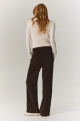 Pantalón de sarga color marrón oscuro, de tiro alto y corte bootcut. Cuenta con pretina ancha con detalle de dos botones en el lateral, pliegues marcados en el frente y bolsillos laterales.