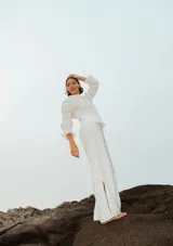 Camisa de lino color marrón rojizo, con cuello clásico y botones frontales blancos. Presenta pliegues verticales en el torso y mangas largas abullonadas con frunces elásticos en los puños.