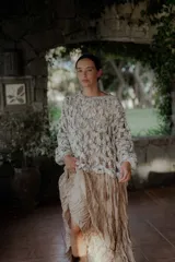 Buzo de tejido de punto calado con diseño de red, cuello redondo y mangas largas abullonadas. Presenta una textura jaspeada en tonos gris y blanco.