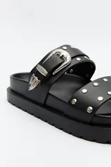Sandalia negra de plataforma con doble tira ancha. La tira superior presenta una hebilla metálica plateada de estilo western y apliques decorativos. La tira inferior tiene tachas metálicas redondas.