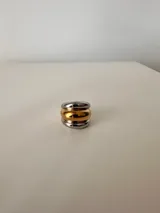 Anillo plateado con una banda central dorada.