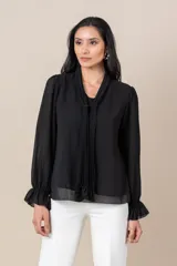 Blusa negra de gasa italiana con cuello con lazo plisado y mangas largas abullonadas con volados en los puños.