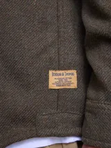 Overshirt de textura tipo tweed en color marrón, con cuello clásico, cierre frontal de botones y bolsillo en el pecho.