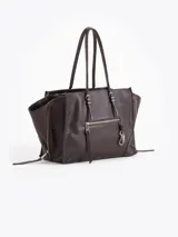 Cartera tote bag pequeña realizada en cuero vacuno marrón, con textura granulada, doble asa de hombro y bolsillos laterales con cierre. Presenta además un bolsillo frontal con cierre y detalle de tiracierres y llavero metálico colgante.
