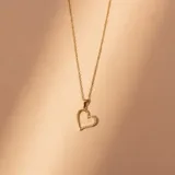 Conjunto de collar y dije en oro 18k. El collar presenta una cadena fina de eslabones y un dije en forma de corazón con incrustaciones de circonias.