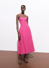 Vestido midi color fucsia, sin mangas, con escote palabra de honor, detalles fruncidos en los laterales del torso y falda evasé.