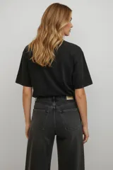 Remera de algodón color negro con efecto lavado, de corte holgado y manga corta. Presenta un estampado frontal con texto y una estrella en tonos claros.