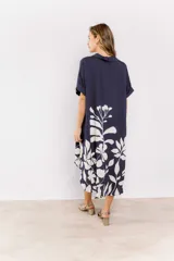 Vestido midi azul marino con estampado de hojas blancas, corte holgado, cuello en V y mangas cortas con dobladillo.
