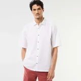 Camisa de manga corta de lino color blanco, con cuello camisero y cierre frontal de botones.