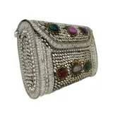 Clutch plateado de estilo hindú, hecho en metal con incrustaciones de piedras de colores. Tiene asa de cadena metálica plateada desmontable.