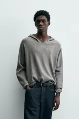 Jersey de lana gris, corte regular, con cuello pico que incorpora una capucha y manga larga. Presenta acabados en rib en puños y bajo.