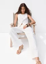 Jeans blancos de silueta balloon, tiro regular y diseño con bordados calados distribuidos en la prenda.