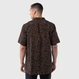 Camisa de manga corta con cuello cubano, confeccionada en viscosa con estampado animal print en tonos marrones y negros. Presenta un bolsillo frontal en el pecho y cierre de botones.