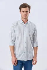 Camisa de manga larga de lino y algodón, con diseño de rayas verticales en tonos celestes y blancos. Presenta cuello camisero, cierre frontal con botones y pequeño bordado al tono en el pecho.