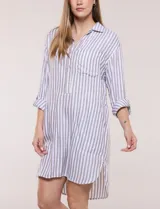 Vestido camisero corto con estampado a rayas verticales en color marrón y blanco, de cuello camisero con escote en V y botones frontales parciales. Cuenta con bolsillos laterales y en el pecho, mangas largas con presillas para ajustar y ruedo curvo asimétrico.