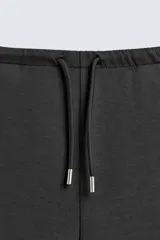 Pantalón de corte baggy fit confeccionado en tejido técnico, con cintura elástica ajustable mediante cordón y bajo con elásticos laterales para ajuste.