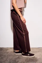 Pantalón deportivo de corte recto y holgado, confeccionado en algodón color marrón chocolate. Presenta una cintura elástica con cordón ajustable y una franja lateral decorativa en tono más claro.