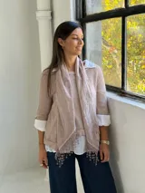 Sweater de punto rosa claro con diseño de capas, que incluye una camisa blanca debajo y un pañuelo a juego con detalles de encaje y flecos en el ruedo.