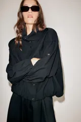 Chaqueta oversize de modal con cuello subido, cierre frontal con botones a presión y mangas largas con puños elásticos. Presenta trabillas en los hombros, bolsillos de vivo en el delantero y bajo abullonado con elástico.