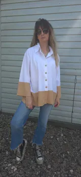 Camisa blanca de lino con mangas largas y corte holgado. Presenta un bloque de color marrón en la parte inferior.