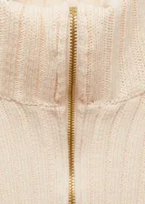 Jersey de punto acanalado en color crema, con cuello alto y cierre frontal de cremallera bidireccional. Presenta un diseño entallado de manga larga con efecto de capas superpuestas.
