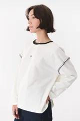 Remera de manga larga con corte oversized, color azul marino con cuello redondo en contraste color marrón. Presenta costuras decorativas a contratono hechas a mano en la zona de los hombros y logo bordado en el centro del pecho.