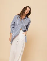 Camisa celeste de algodón con corte oversized, botones frontales a tono y vivos blancos ondulados en el frente.