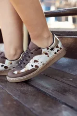Championes de diseño artesanal con paneles de cuero vacuno con pelo estampado tipo animal print y detalles en cuero liso marrón. Presenta una pieza metalizada en el talón y suela de goma color caramelo.