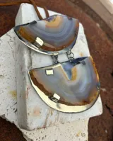 Collar de tiento de cuero con dije colgante compuesto por dos piezas de piedra ágata azul engarzadas en metal plateado.
