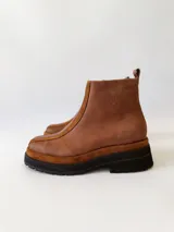 Botas cortas de cuero color marrón con elástico en los laterales y detalle de cuero texturizado en la parte delantera.