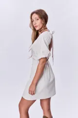 Vestido corto color beige de lino, con escote cuadrado, mangas cortas abullonadas y corte a la cintura.