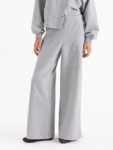 Pantalon de corte recto y silueta holgada, confeccionado en tejido rustico de algodon. Presenta cintura elastizada y detalles de broches a presion metalicos en los laterales, fusionando un estilo deportivo con elementos de diseño sastrero.