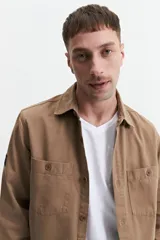 Sobrecamisa verde militar de twill de algodón, con cuello clásico, cierre frontal con botones a tono, dos bolsillos tipo parche con solapa abotonada en el pecho, mangas largas con puños abotonados y corte recto.