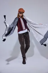 Chal de lana con diseño de patrón paisley y detalles de tejido en punto. Presenta terminaciones con pompones en los extremos.