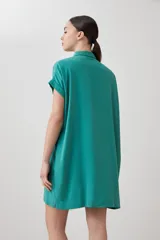 Túnica verde de lyocell con cuello camisero, manga corta con dobladillo y cierre frontal con botones.