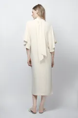 Vestido midi fluido de cuello alto y manga corta tipo capa. Presenta un diseño minimalista con bajo recto y aberturas laterales, con cierre en la espalda.