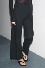 Jeans de tiro alto, pierna ancha y largo al tobillo, en denim celeste claro con efecto lavado. Presenta costura marcada en el centro de cada pierna y cierre frontal con cremallera y botón.