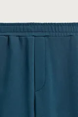 Pantalón jogger de corte relajado y pernera ancha, confeccionado en tejido de algodón con interior perchado. Cuenta con cintura elástica ajustable mediante cordón interior, bolsillos laterales y un bolsillo trasero de plastrón.