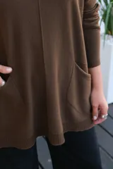 Sweater de tejido de punto en color chocolate, con corte holgado, cuello redondo y mangas largas. Presenta un diseño con bolsillos frontales integrados y terminaciones acanaladas en puños y ruedo.