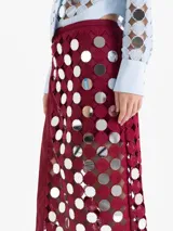 Pollera midi cruzada confeccionada en guipur color bordó con espejos circulares bordados. Presenta una abertura lateral y forrería interna al tono.