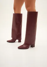 Botas negras de caña alta confeccionadas en cuero vegano, con punta fina y taco cuadrado.