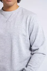 Buzo clásico de cuello redondo y manga larga, en color gris melange. Presenta un ajuste regular y un logo bordado con detalle en goma en el pecho.