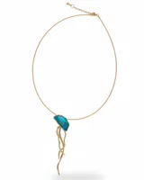 Collar de cadena fina dorada con un dije artesanal en forma de medusa, elaborado en bronce con detalles en resina de color turquesa.