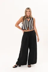 Pantalón negro de pierna súper amplia, confeccionado en denim fino y liviano con caída fluida. Tiene cintura elastizada con lazo regulable, bolsillos laterales y pinzas en la delantera.